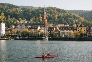 Canoe on river near city and mountains